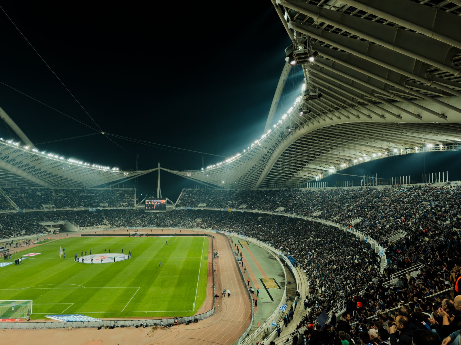 A floodlit stadium at night, full of spectators